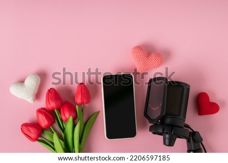 Love on the Internet. Smartphone and microphone with a bouquet of tulips. Banner for Valentine's Day. Postcard for February 14.Love. Minimalism. A place to copy. Flat position, top view.