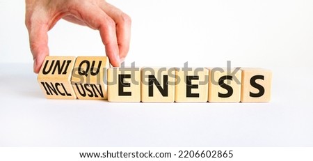 Inclusiveness and uniqueness symbol. Businessman turns wooden cubes, changes words inclusiveness to uniqueness. Beautiful white background. Business, inclusiveness and uniqueness concept. Copy space.