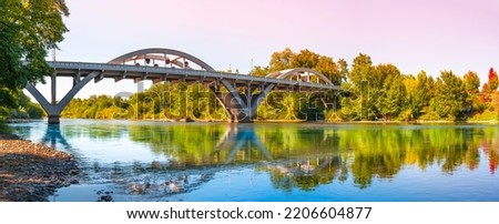 Rogue River Bridge, spanning Redwood Highway 25 in Grants Pass, Josephine County, Oregon. The arching bridge reflected on Rogue River at sunset. Royalty-Free Stock Photo #2206604877