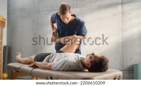 Advanced Sport Physiotherapy Specialist Stretching and Working on Muscle Groups or Joints with Young Male Athlete. Fit Sportsman Recovering from Mild Injury, Undergoing Rehabilitation. Royalty-Free Stock Photo #2206610209