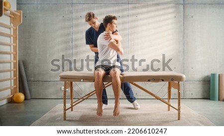 Professional Sport Physiotherapist Working on Specific Muscle Groups and Back Pain with Young Male Athlete. Sportsman Recovering from Mild Injury. Trauma Prevention Therapy or Rehabilitation. Royalty-Free Stock Photo #2206610247