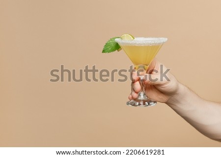 Close up cropped barman bartender male holding in hand martini alcohol cocktail glass isolated on plain pastel light beige wall background studio. Bar party concept. Copy space advertising mock up. Royalty-Free Stock Photo #2206619281