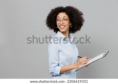 Young employee business corporate lawyer woman of African American ethnicity in classic formal shirt work in office clipboard with papers document look aside on workspace isolated on grey background Royalty-Free Stock Photo #2206619331