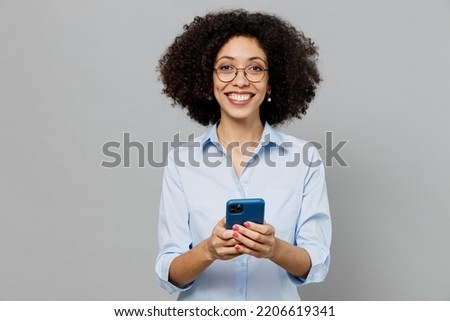 Young happy employee business corporate lawyer woman of African American ethnicity in classic formal shirt work in office hold in hand use mobile cell phone isolated on grey color background studio