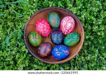 happy easter eggs in wooden bowl on a grass with flowers