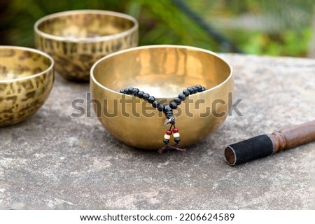 Tibetan singing bowls with sticks on the concrete grey background outdoors. Sound healing music instruments for meditation, relaxation, yoga, massage, mental health