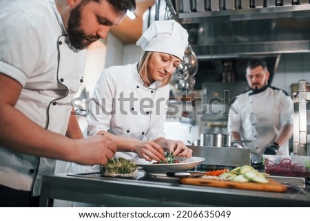 Team making salad. Professional chef preparing food in the kitchen.