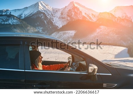 Woman traveling, exploring, enjoying the view of the mountains, landscape, lifestyle concept winter vacation outdoors. Female driving a car in sunny day, travel in the mountains, freedom and active