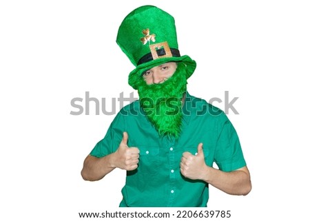 A cheerful white-skinned man in a leprechaun costume with shamrock isolated on the white background.Smiling guy in green hat, shirt and with beard.Banner for St. Patrick's Day in Ireland.Copy space