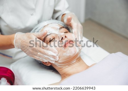 the cosmetologist cleanses the skin with foam. A woman's skin care procedure. Natural cosmetics. A beautiful face. Cosmetic treatment of the face. Therapeutic peeling cream. Royalty-Free Stock Photo #2206639943