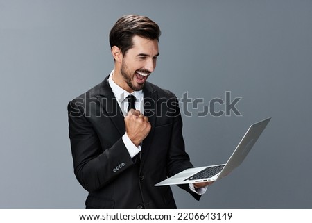 Man business looks into laptop and works online smiling fist bump online in business suit video call business negotiations win on gray background copy place Royalty-Free Stock Photo #2206643149
