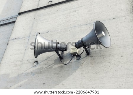 Pair of big retro loudspeakers mounted on grey concrete cement wall. Air raid nuclear strike alert speaker siren. Urgent or emergency announcement, message event. Dictatorship regime concept Royalty-Free Stock Photo #2206647981