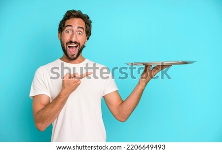young crazy bearded and expressive man holding an empty steel tray
