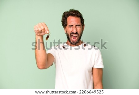 young crazy bearded and expressive man holding an insect with the fingers