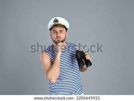 Thoughtful sailor with binoculars on light grey background
