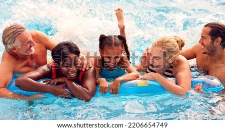 Smiling Multi-Generation Family On Summer Holiday Relaxing In Swimming Pool On Airbed Royalty-Free Stock Photo #2206654749