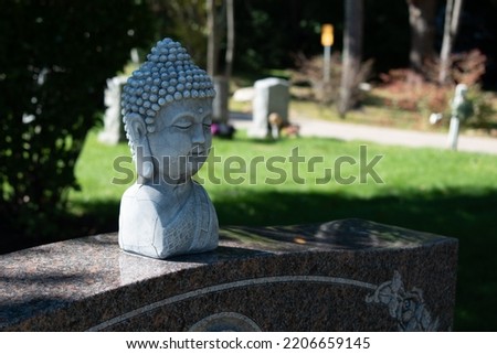 Buddha statue resting upon a Christian gravestone in a New England