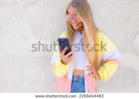 Smiling teenage girl standing outdoors and using mobile phone