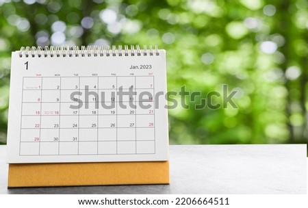 January 2023 desk calendar for planners and reminders on a black table on the natural background green .