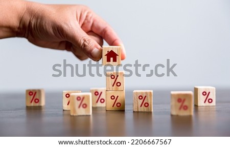 Hand building a house by wooden cubes with the percentage sign on them. Concept of Interest rate financial mortgage rates, home loans, home refinance, wooden block with percentage symbol and up arrow.