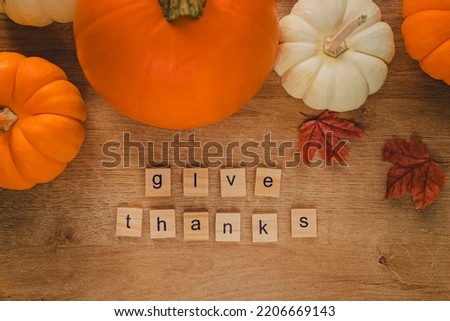 Thanksgiving flat lay composition. Pumpkins, leaves and text Give Thanks arranged from the wooden letters