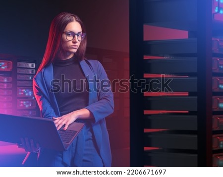 IT specialist woman. Girl with laptop in server room. Woman works as system administrator. Young businesswoman next to servers. IT business owner concept. IT company employee and server hardware