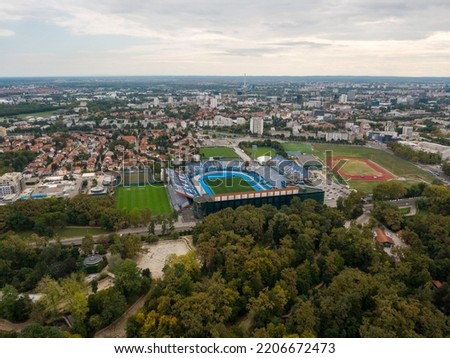 A Drone shot of a beautiful city with red roof buildings and a green stadium  in Zagreb, Croatia