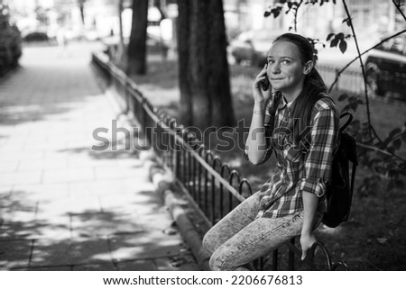A teengirl talking on smartphone in a Park. Black and white photo.