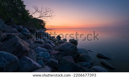 wonderful colorful sunset on a calm sea with a rocky shore Royalty-Free Stock Photo #2206677393