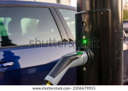 Electric car being charged from a charging point on a street light post. Royalty-Free Stock Photo #2206679055