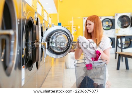 European woman washing her clothes by a washing machine in laundry shop Royalty-Free Stock Photo #2206679877