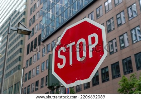 A closeup shot of a stop sign and a modern building in the background