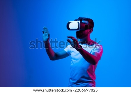 Bearded ambitious modern male working in VR glasses while pointing with finger on a subject in virtual reality.