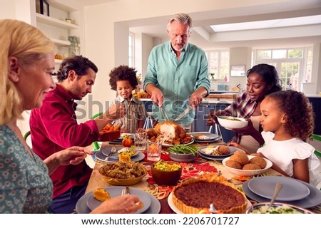 Grandfather Serving As Multi-Generation Family Celebrating Thanksgiving At Home Eating Meal Together
