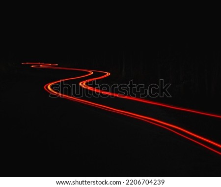 A winding car light trail in the darkness Royalty-Free Stock Photo #2206704239