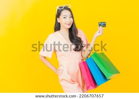 Portrait beautiful young asian woman smile with shopping bag on color background