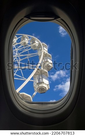 Airplane window. Ferris wheel with clouds in the window of the aircraft.