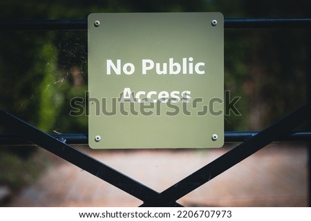 A closeup shot of a sign of no public access hanging on a metal black gate