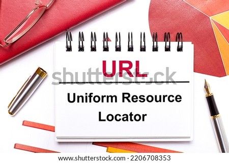 On the desktop is a white notebook with the text URL Uniform Resource Locator, a pen, burgundy and red tables, and gold-framed glasses. Business concept.