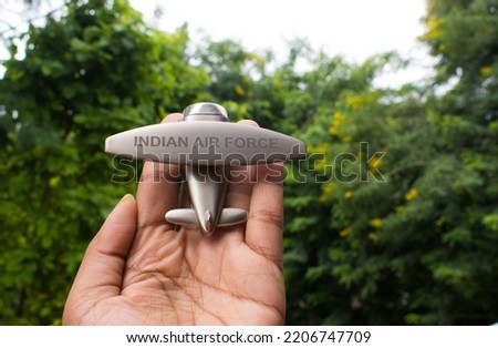 Holding fighter plane toy in hand. Writter Indian Air Force. selective focus, background blur.