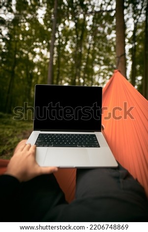 POV of a Tourist working remotely with Laptop Computer. Traveller Resting in a hammock in the forest. Adventurous Hiker Living in Nature.
