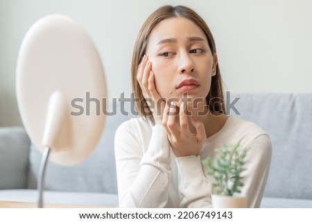Expression worry asian young woman hand touching pustule around the chin and mouth, allergic when wear mask, makeup, show squeezing pimple spot from face. Beauty care, skin problem by acne treatment. Royalty-Free Stock Photo #2206749143