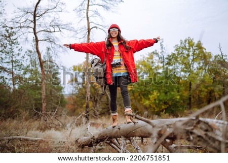 Young woman- tourist taking pictures in the autumn forest.  Rest, relaxation, tourism, nature, lifestyle concept.