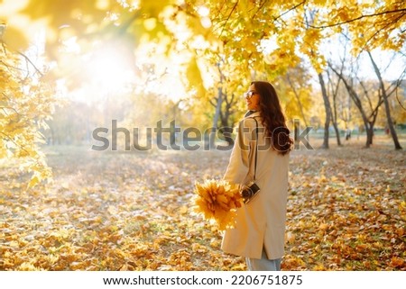 Beautiful woman taking pictures in the autumn forest.  Rest, relaxation, tourism, lifestyle concept.