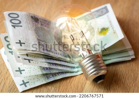 Polish money Several hundred Polish zlotys and a light bulb, the concept of increasing energy and electricity prices in Poland Royalty-Free Stock Photo #2206767571