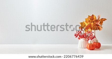 Home interior with decor elements. Colorful autumn leaves in a vase on a light background. Mock up for displaying works Royalty-Free Stock Photo #2206776439