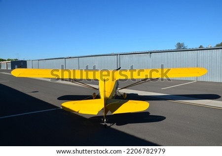 Bright yellow 1946 vintage airplane.  Picture is taken from behind the plane as it starts to taxi.