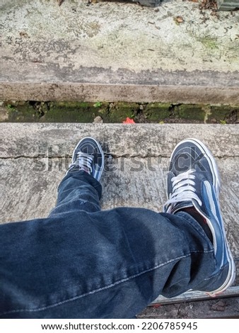 photo of a man sitting cross-legged wearing jeans and shoes