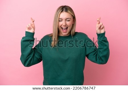 Young caucasian woman isolated on pink background with fingers crossing Royalty-Free Stock Photo #2206786747