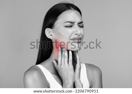 Black and white photo of young sick lady suffering from tonsillitis, pulping her lightened in red neck, experiensing acute throat pain, copy space, closeup Royalty-Free Stock Photo #2206790951